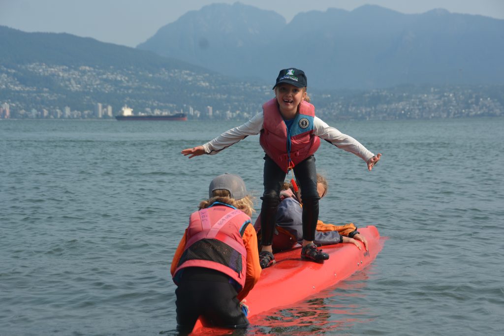kid standing on upside down kayak